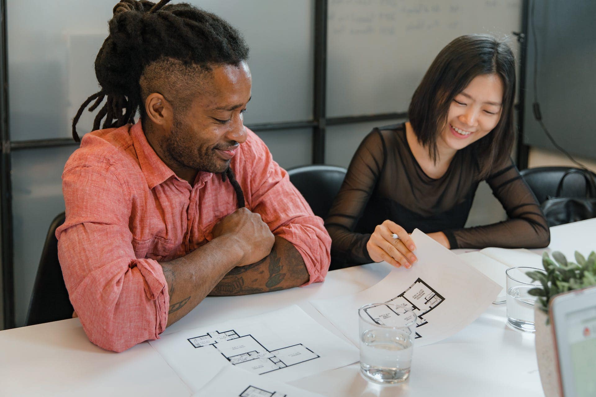 Two people sitting at a table looking at blueprints.